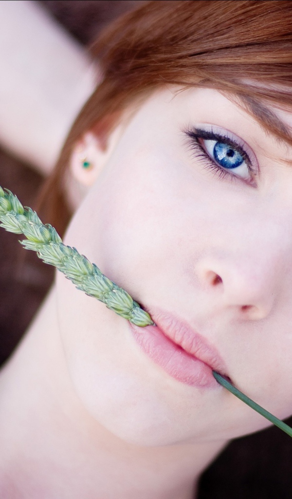 Зеленый колосок во рту у девушки