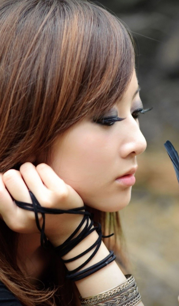 Японская девушка смотрит на черное перо