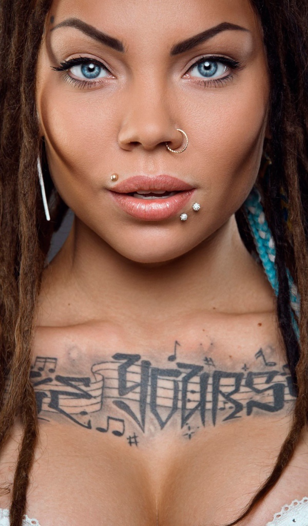 Музыкальное тату на груди у девушки с кольцом в носу