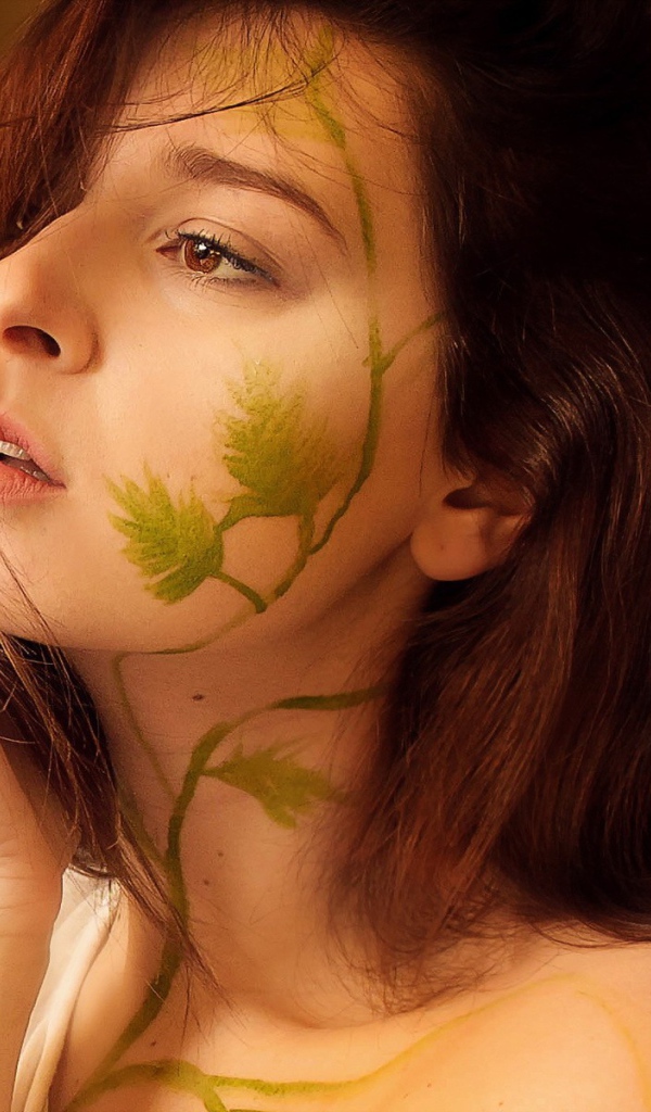 Рисунок зеленых листьев на лице и шее девушки