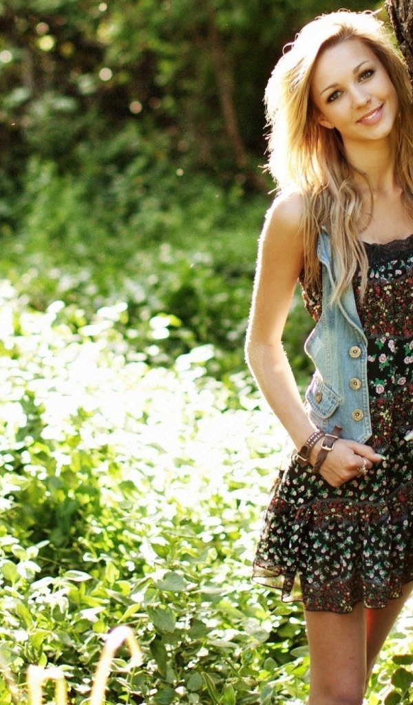 Милая блондинка прислонилась у дерева