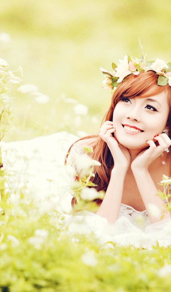 Рыжая японская девушка лежит в поле цветов