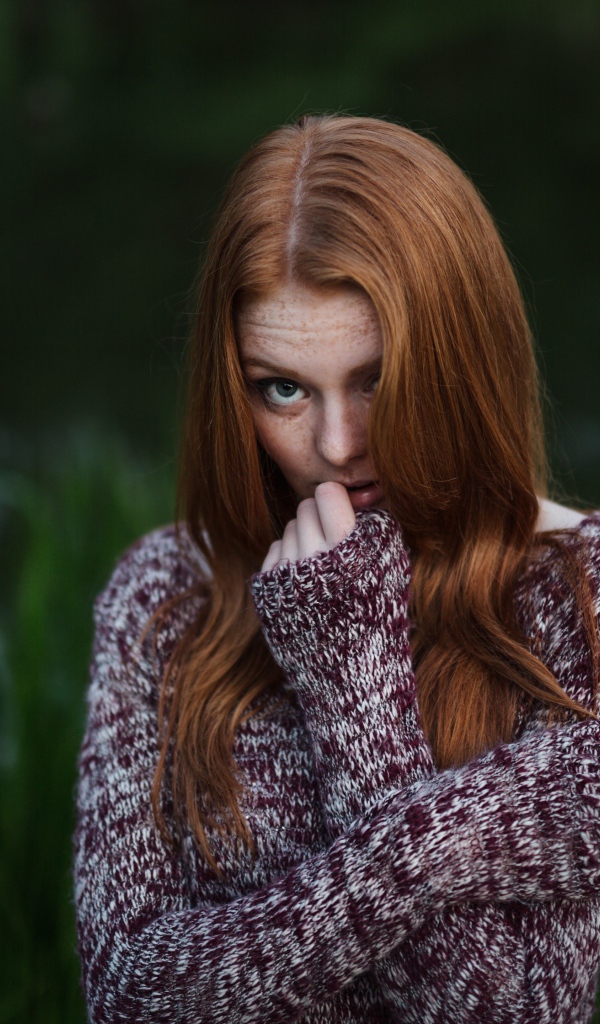 Рыжая девушка в свитере на фоне водоема