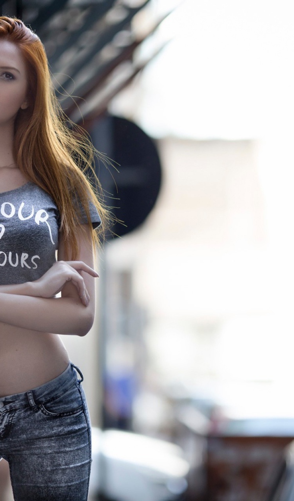 Рыжая девушка в джинсах с надписью на топике