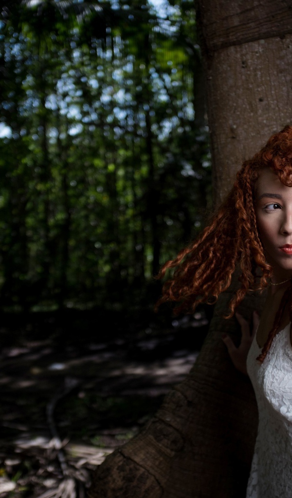 Рыжая девушка с кудрями у большого дерева