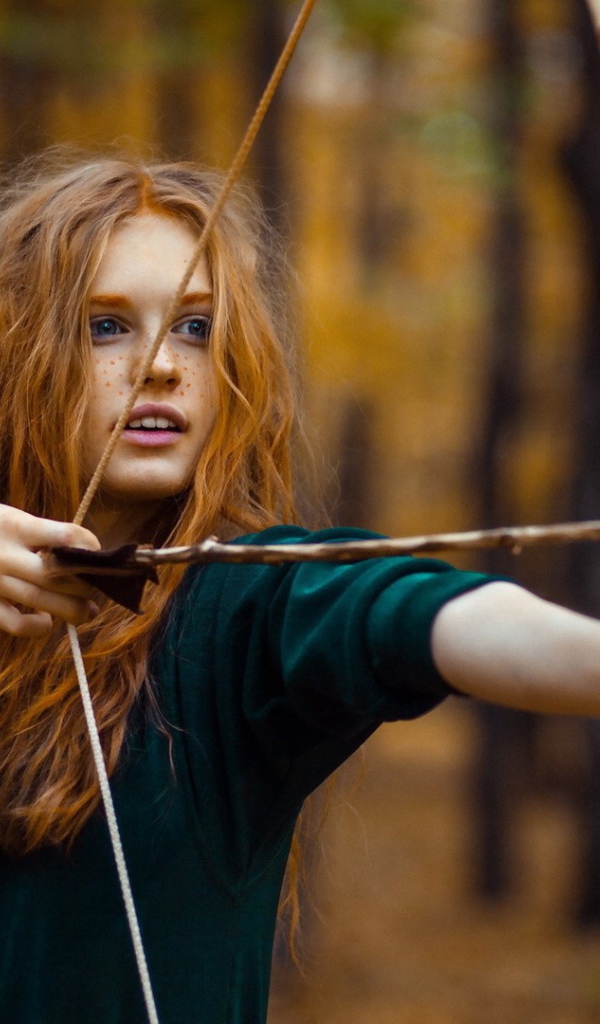 Рыжая девушка целится из лука