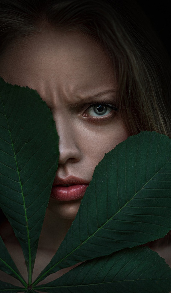 Девушка прикрыла лицо листьями каштана