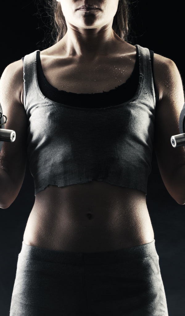 Спортивная девушка с гантелями в руках