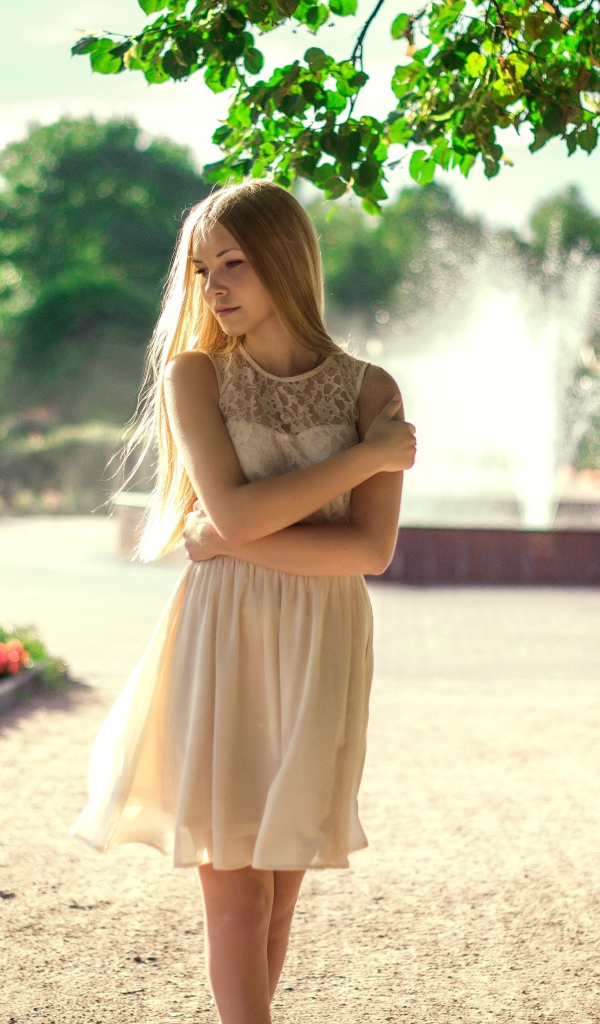 Блондинка в парке на фоне фонтана