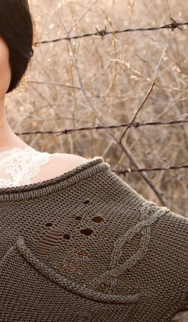 Девушка у забора из колючей проволоки