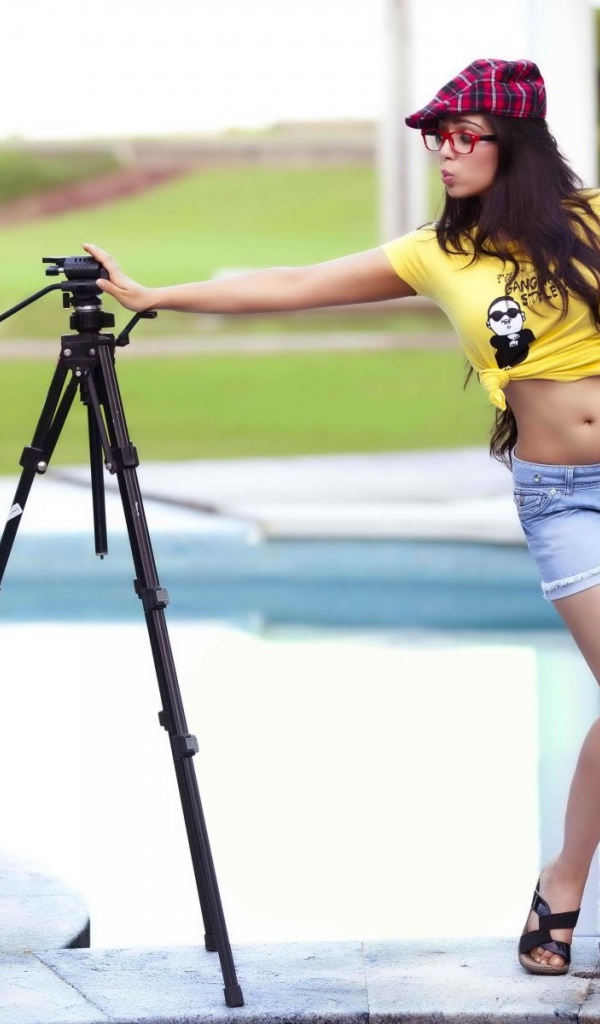 Девушка у бассейна с треногой для фотоаппарата