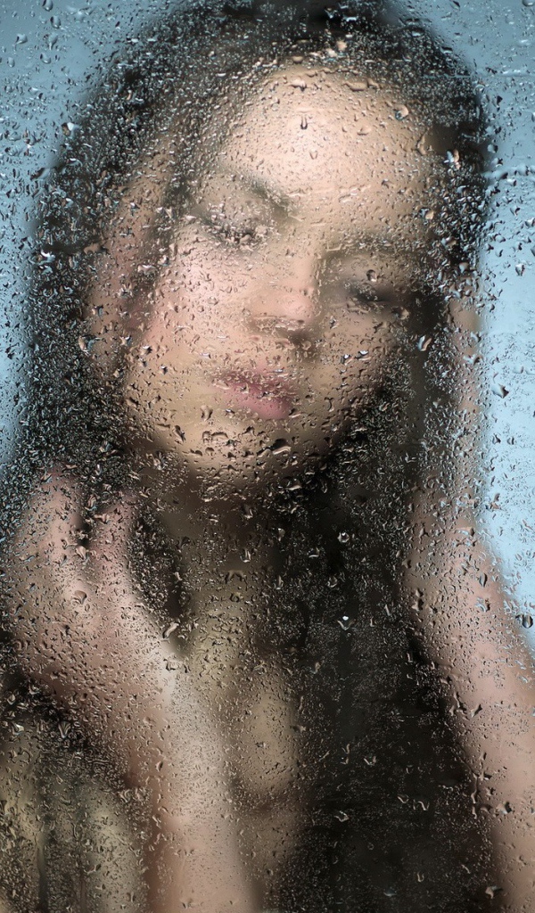 Девушка позади мокрого стекла