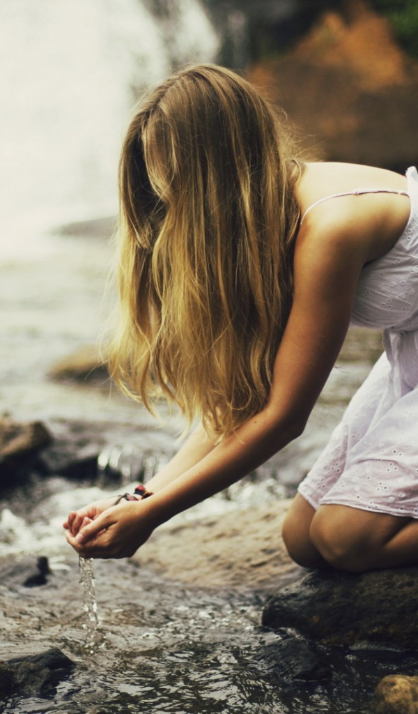 Девушка черпает воду из ручья