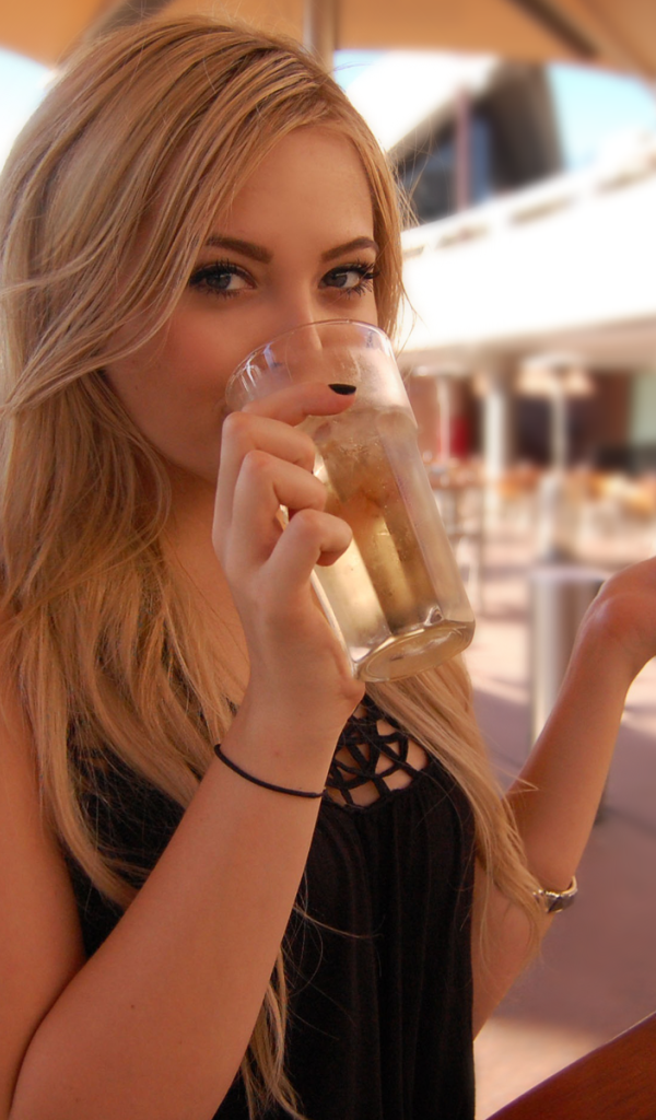 Девушка пьет из стакана в кафе