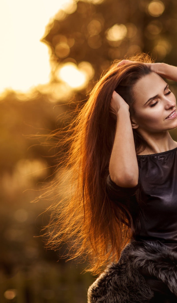 Девушка в черном платье поправляет прическу, портрет
