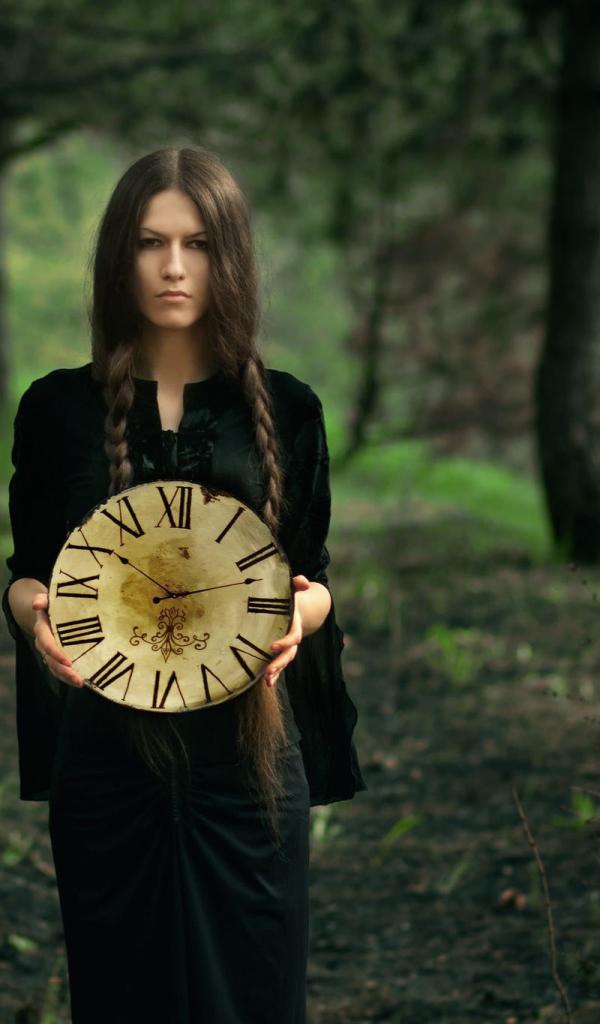 Девушка в черном платье держит часы в руках