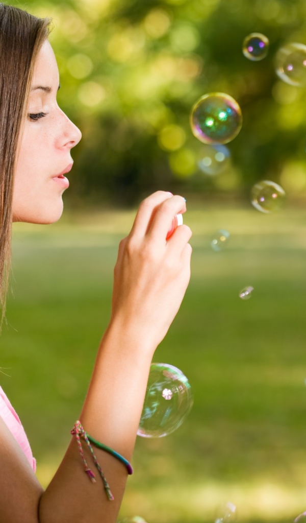 Девушка в розовой футболке запускает мыльные пузыри