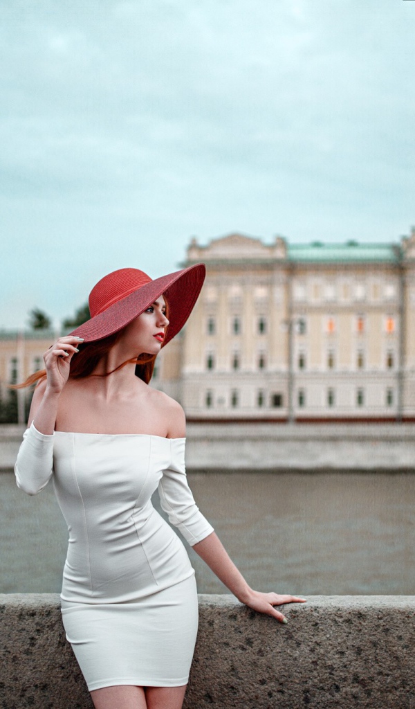 Девушка в белом платье и красной шляпе на набережной