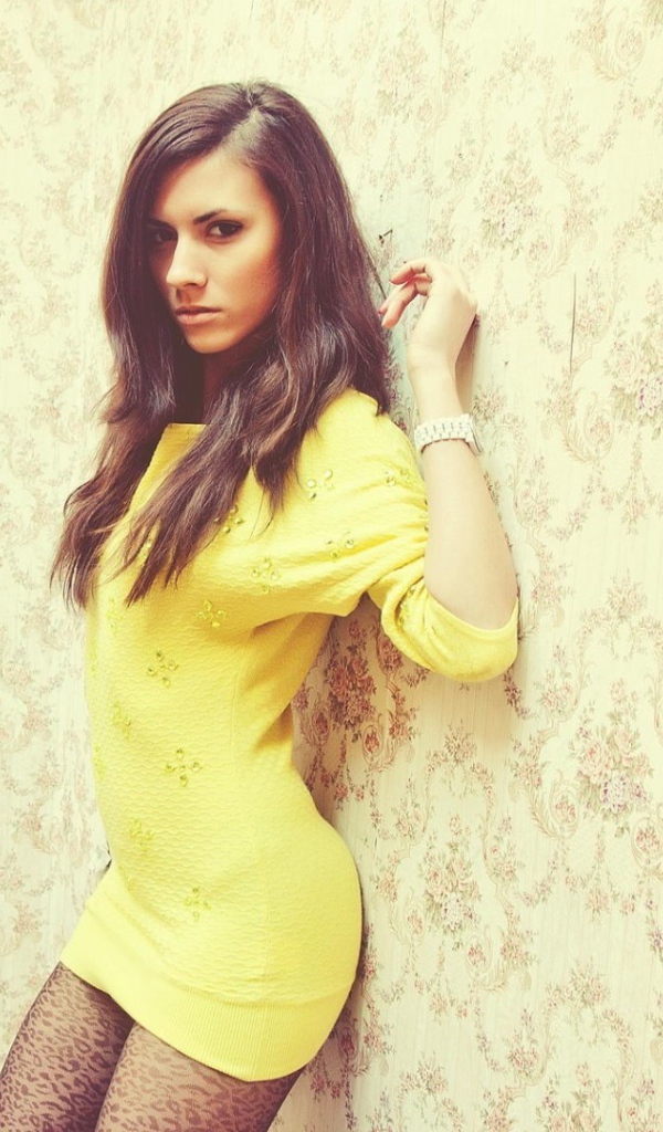 Девушка в желтом платье прислонилась к стене