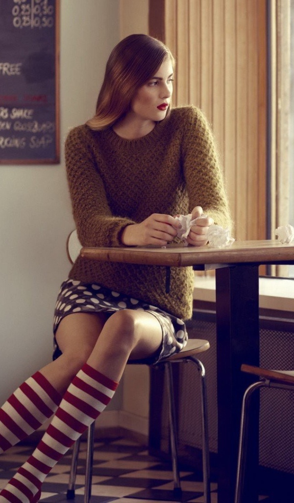 Девушка в полосатых чулках смотрит в окно