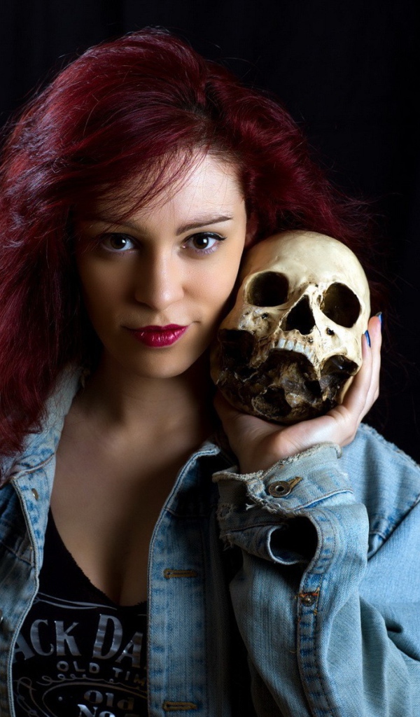 Девушка в джинсовой куртке держит череп на плече