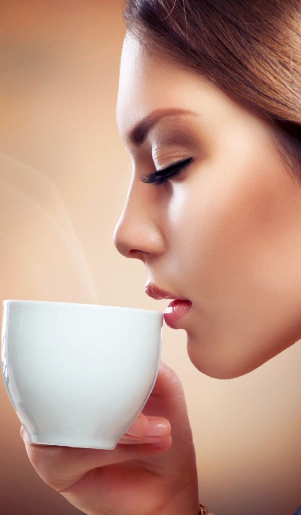 Девушка вдыхает аромат кофе
