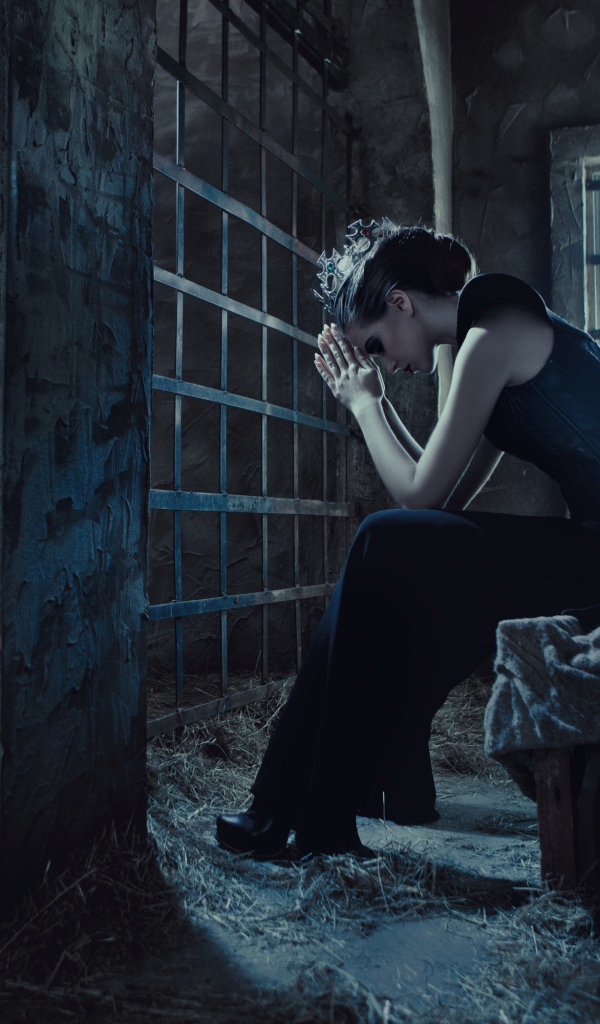 Девушка сидит за решеткой в тюрьме