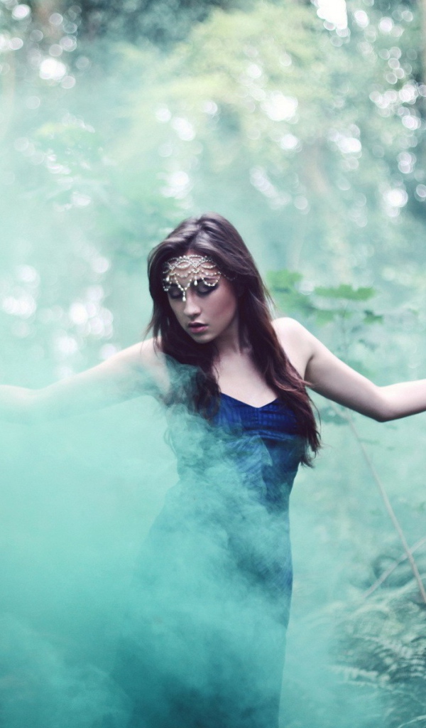 Девушка идет среди дыма по лесу