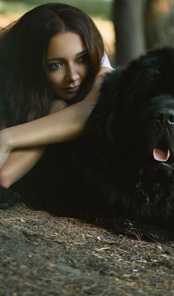 Девушка лежит на большой черной собаке