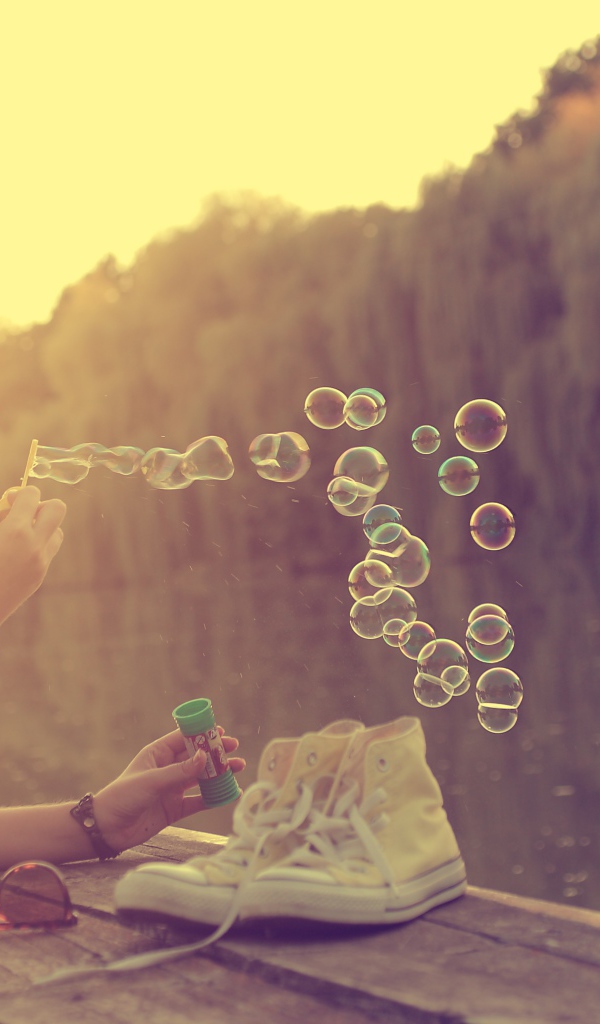 Девушка лежит на пирсе и играет с мыльными пузырями