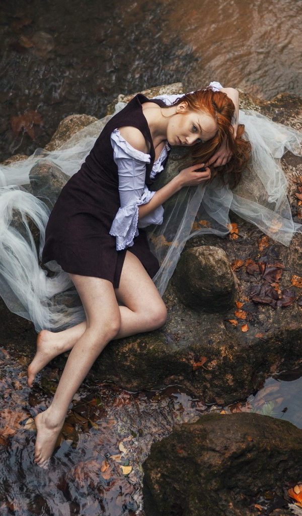 Девушка лежит на камне среди воды