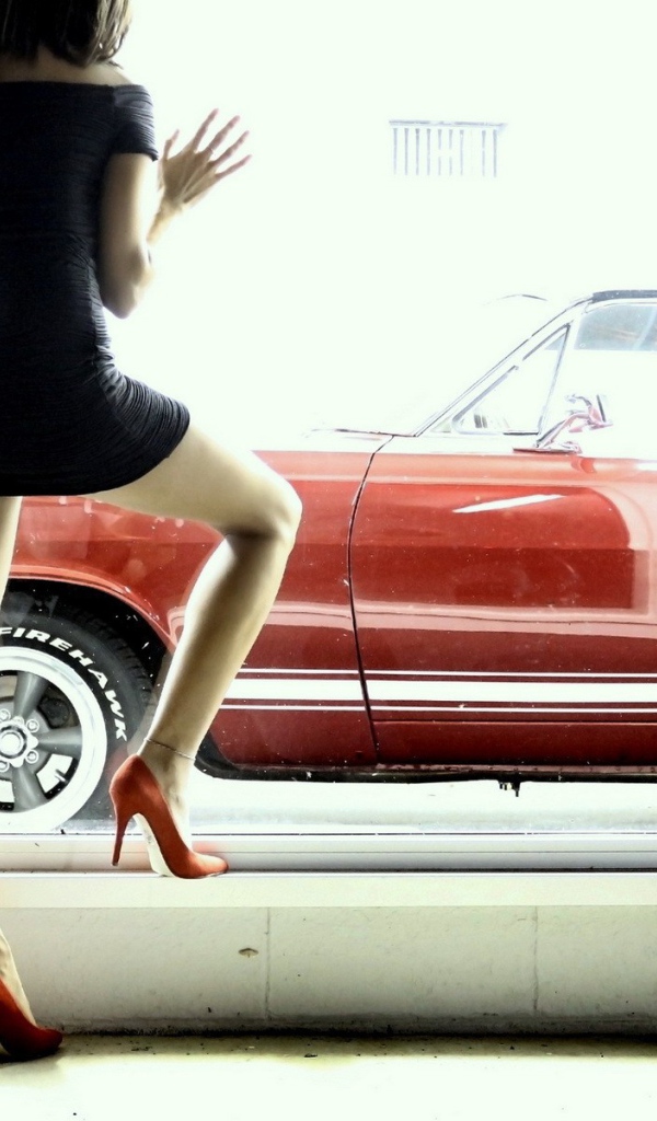 Девушка смотрит в окно на красный автомобиль