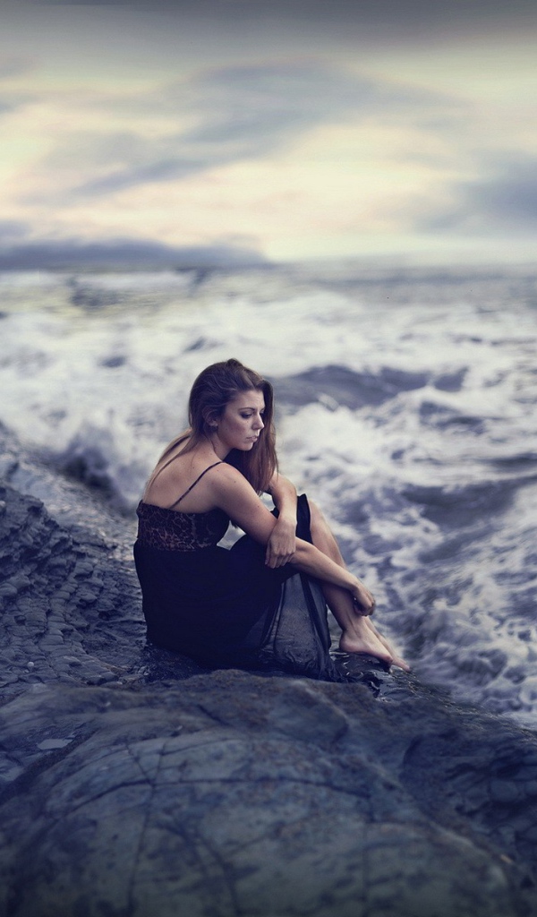 Девушка на скале смотрит в бурное море