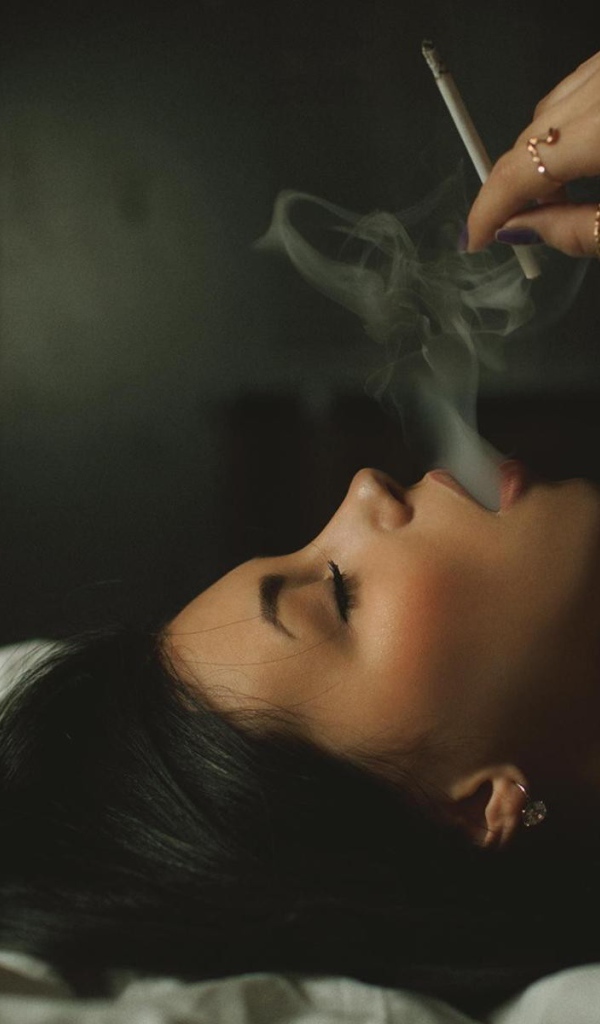Девушка курит лежа в постели