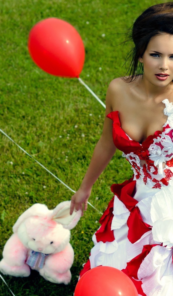 Девушка с игрушкой среди красных воздушных шариков