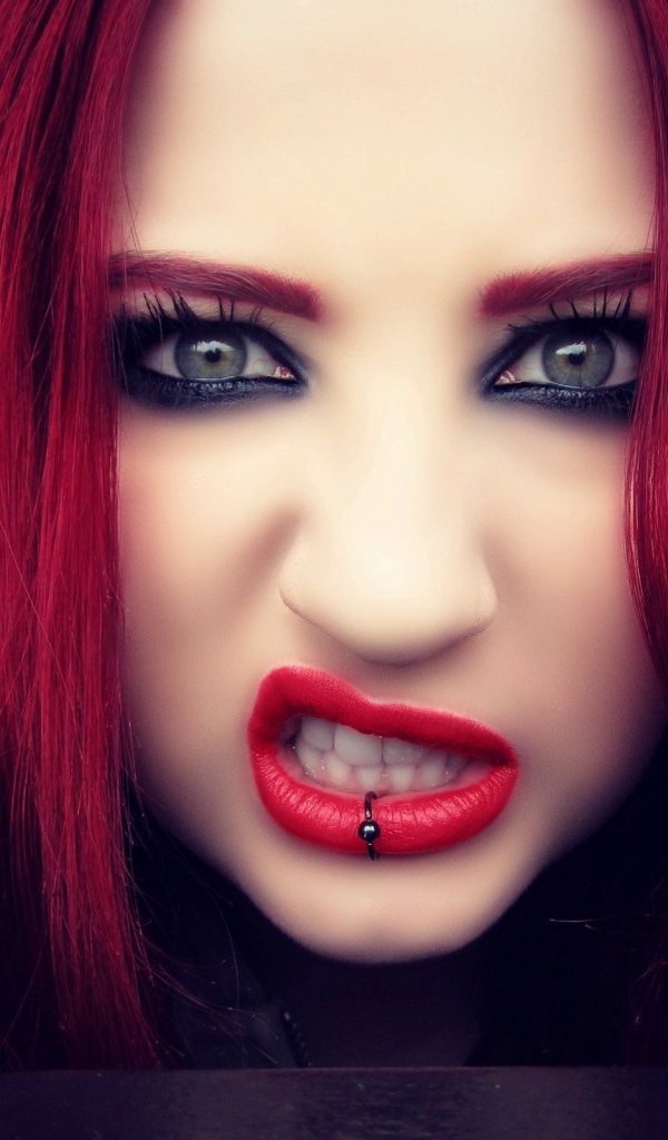 Девушка с красными волосами показывает зубы