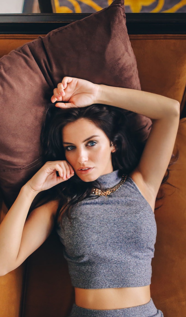 Модель Aurela Skandaj лежит на диване