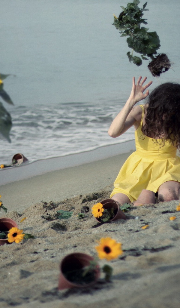 Модель в желтом платье среди цветов на пляже