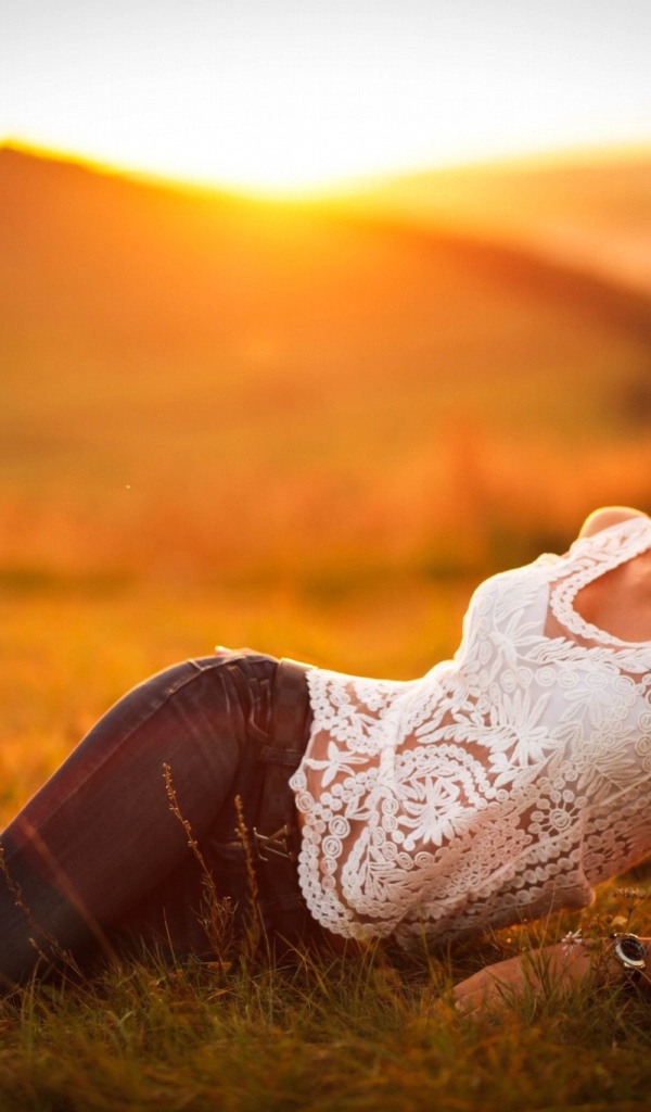 Модель в джинсах позирует на закате солнца