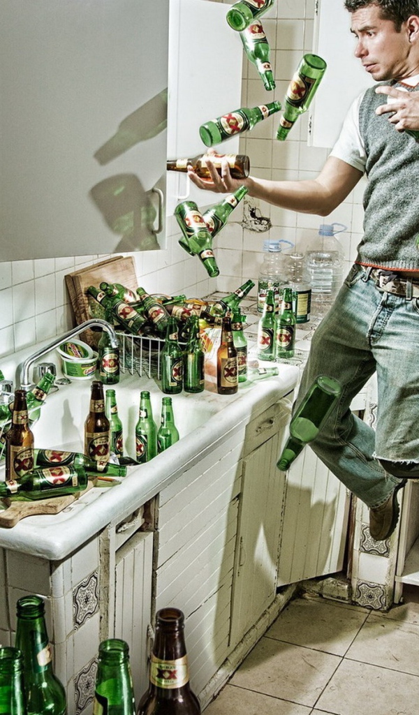 Мужчина среди бутылок пива на кухне