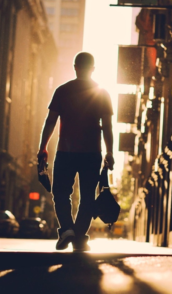 A man walks down the street towards the sun