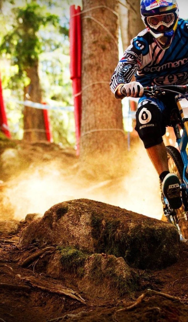 Мотобайкер объезжает камень в лесу