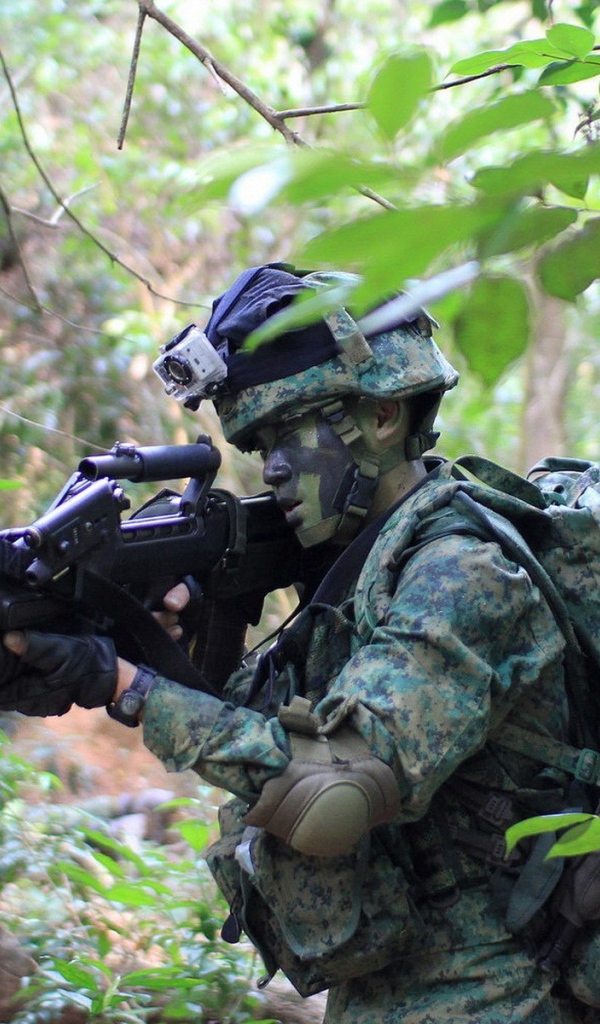 Солдат в камуфляже идет по лесу