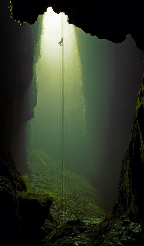 Спелеолог спускается по канату в пещеру