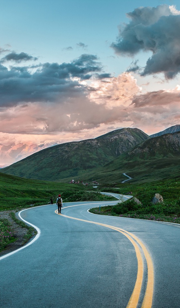 Одинокий путник на шоссе среди гор