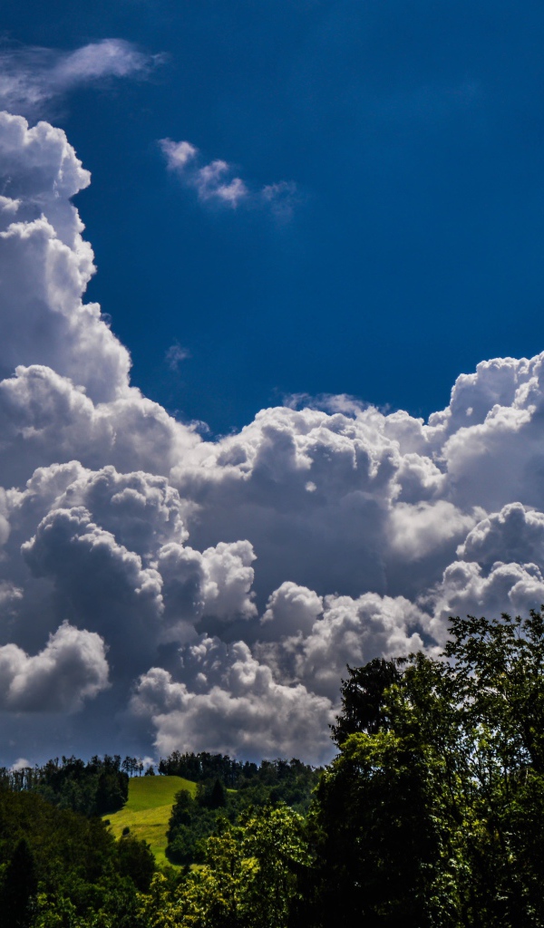 Кучевые облака над зелеными холмами