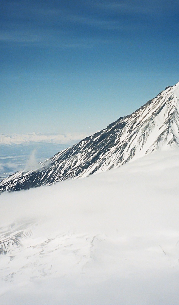 Вершина покрытой снегом горы в облаке