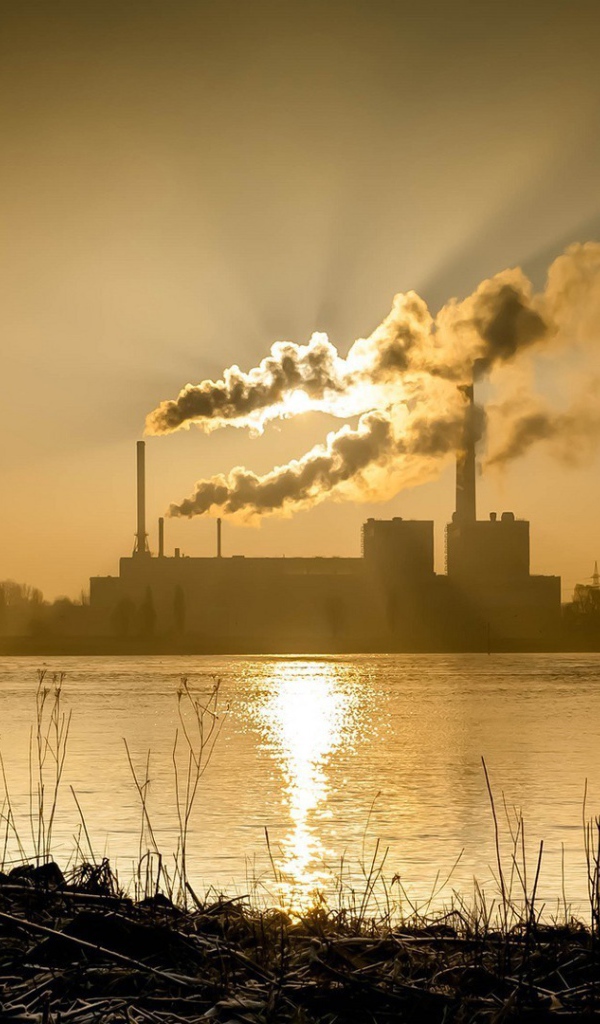 Лучи солнца пронизывают дым из заводских труб