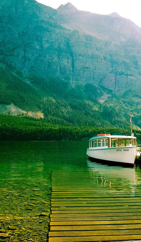 Лодка у причала на зеленой воде горного озера