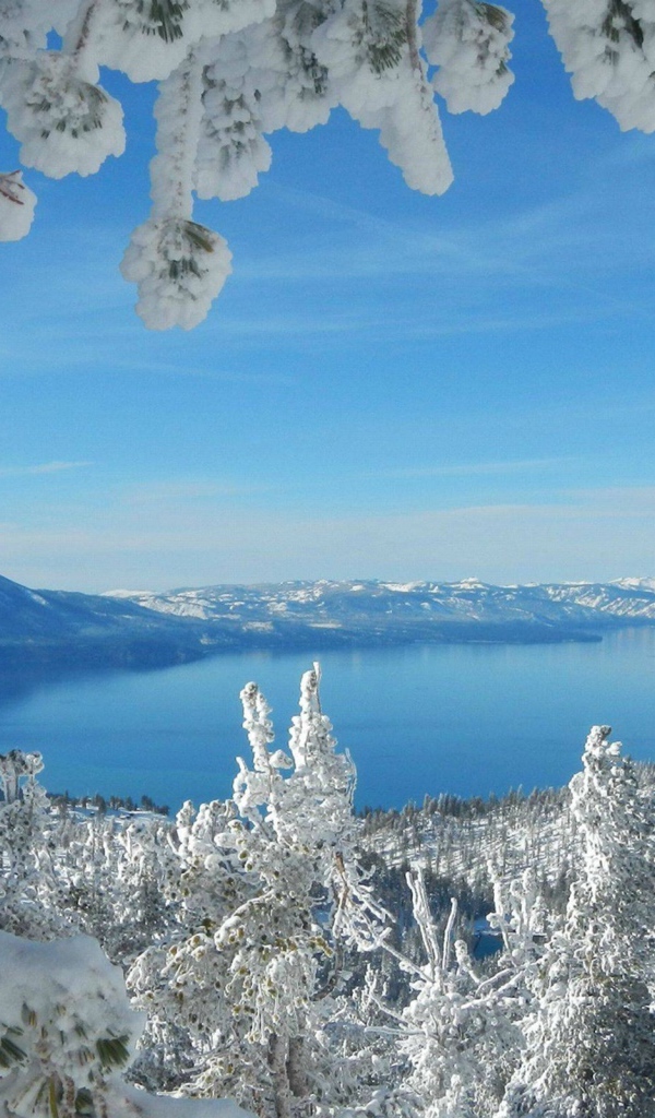 Горное озеро в рамке из заснеженных ветвей